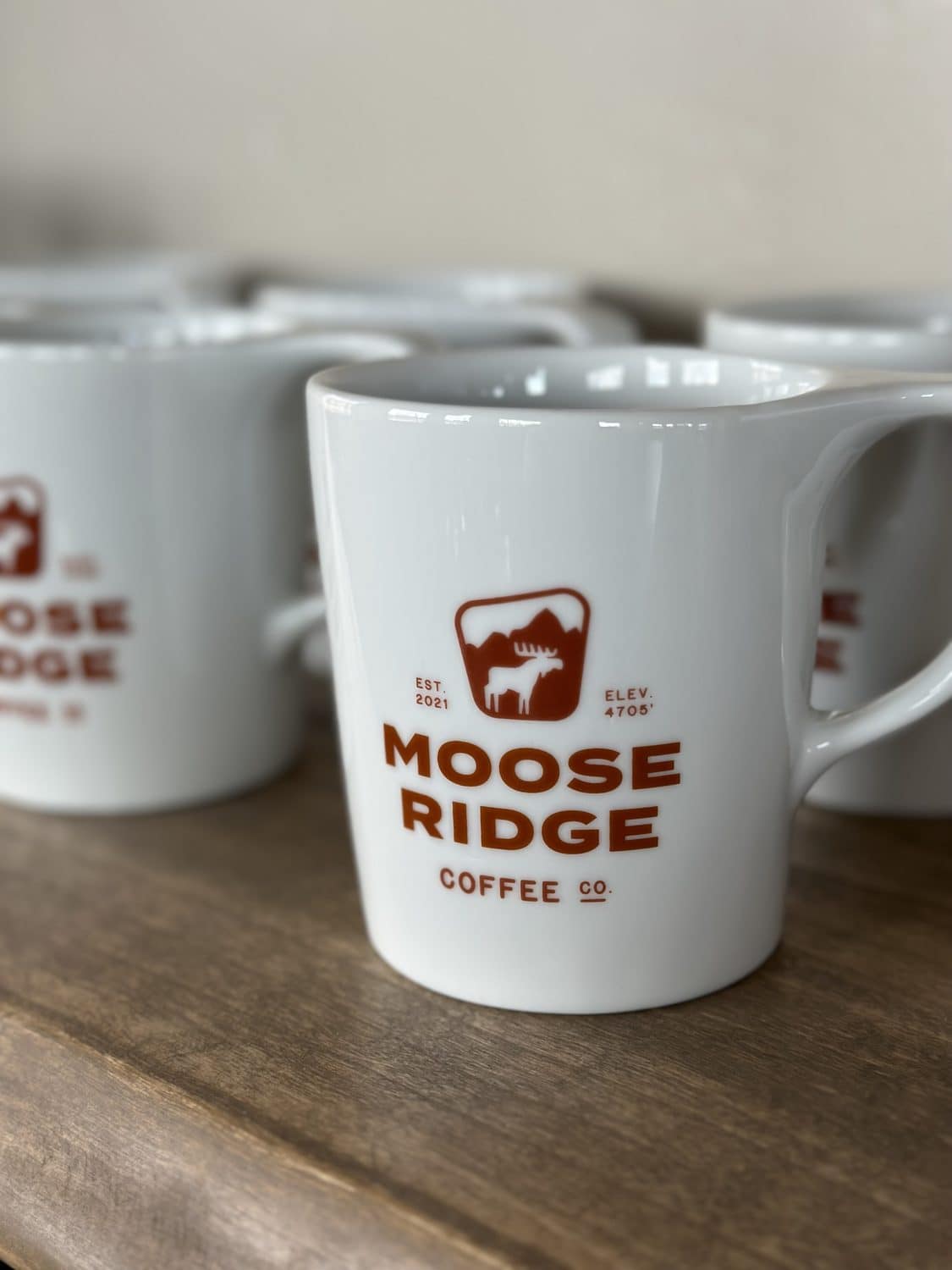 Moose Ridge branded mugs on a wood shelf